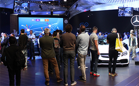Attendees exploring an interactive automotive trade show exhibit featuring digital displays and vehicle presentations. Attendees exploring an interactive automotive trade show exhibit featuring digital displays and vehicle presentations.
